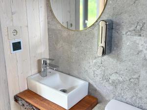 une salle de bain avec un lavabo blanc et un miroir dans l'établissement Rātes Krasti - PĒRLE- holiday house with sauna and lakeview, à Lejasciems