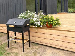 un barbecue sur un support à côté d'une jardinière dans l'établissement Rātes Krasti - PĒRLE- holiday house with sauna and lakeview, à Lejasciems 25 autres photos