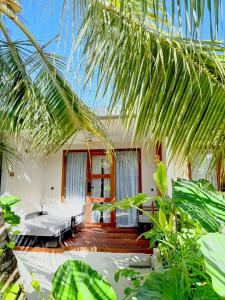 a room with a bed and some palm trees at Raakani Dhigurah in Dhigurah +14 photos