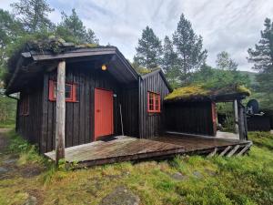 a cabin with a wooden deck with a grass roof at Hov Hyttegrend in Viksdalen