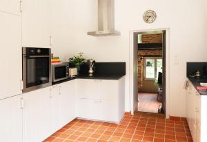 a kitchen with white cabinets and a red tile floor at House Nestled in the Forest in Vieux-Viel +6 photos