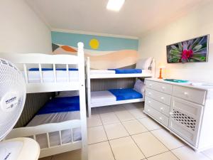 a bedroom with two bunk beds and a desk at Recantos Pinheiros - Casa inteira, até 15 hóspedes - Piscina privativa, sinuca, ar condicionado e TVs nos 4 quartos - Condomínio Orla 500, lado praia - Unamar, Cabo Frio-RJ in Tamoios +37 photos