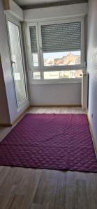 Una gran alfombra morada en una habitación con ventana. en A private room in a flat shared familly home, en Mulhouse