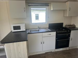 a small kitchen with a sink and a microwave at Ty - Bach in Chwilog