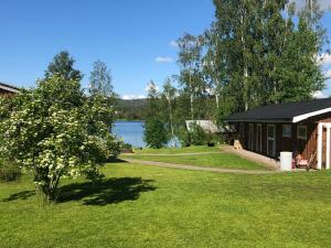 a cabin with a grassy yard next to a lake at Sjönära lägenghet på landet in Fränsta