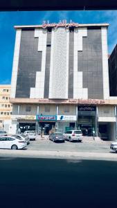 a large building with cars parked in front of it at شقق دار الفرسان المخدومة in Quai