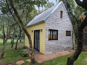 a small yellow and white house in the woods at Tiny House na Pousada Hortelã-Pimenta in Itirapina
