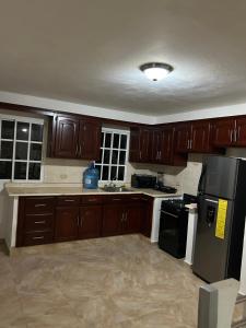 a kitchen with wooden cabinets and a black refrigerator at Villas Maniscalco in Camú