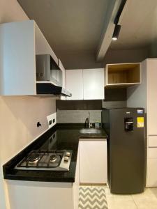 a small kitchen with a stove and a refrigerator at BOHÍO del Pescador Barquero - Diverso y con Alma in Medellín
