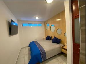 a bedroom with a bed with blue pillows and mirrors at Edificio Confort in San Felipe Hueyotlipan