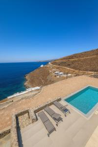 a swimming pool with lounge chairs and the ocean at Kythnos Sunset View Villa in Flampouria