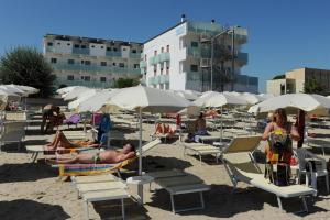 un grupo de personas sentadas en la playa bajo sombrillas en EuroHotel, en Cesenatico
