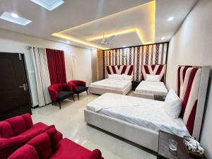 a hotel room with two beds and red chairs at Sweet Villa Guest house Islamabad G9-4 in Islamabad