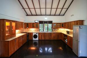 a large kitchen with wooden cabinets and a refrigerator at Ricco Tara Villa in Boossa