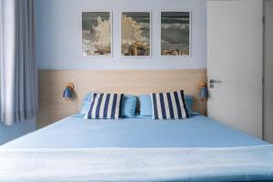 - une chambre avec un lit bleu et deux oreillers à rayures dans l'établissement Apartamento a 5min da Praia do Forte Luxo e Conforto, à Škorak