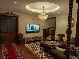 a living room with a couch and a tv at Modern Super Lux Mohandessin Flat Perfect for Gulf Travelers in Cairo