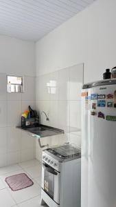 a white kitchen with a stove and a refrigerator at Quarto Casal em Barreirinhas-MA in Barreirinhas