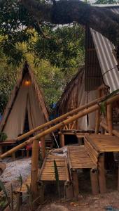 un groupe de tentes avec des bancs sous un arbre dans l'établissement Green House Chalé, hostel e pousada, à Saquarema