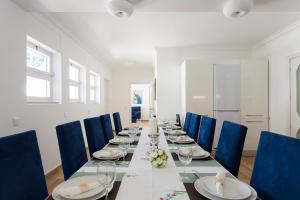 a long dining room with a long table and blue chairs at Villa Branca do Castelo in Sesimbra