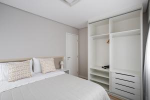 a white bedroom with a white bed and shelves at Apto 2qts, Ar Condicionado, Piscina, Churrasqueira, Finamente Mobiliado e Decorado in Curitiba +20 photos