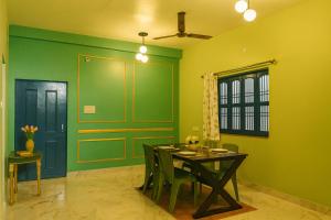 a dining room with green walls and a table and chairs at Kashivas - 2BHK near Assi Ghat in Varanasi +34 photos
