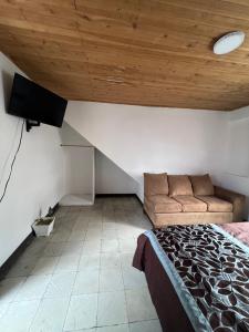 a bedroom with a bed and a couch and a wooden ceiling at El refugio santarrosano in Santa Rosa de Cabal