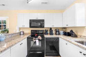 a kitchen with white cabinets and a black oven at Fairway View Escape - For 8 in Branson
