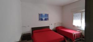 a bedroom with two red beds and a window at La Zinnie Salentina in San Pietro in Bevagna