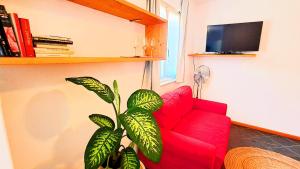 a red chair and a plant in a living room at a 200m dai mercatini TERRAZZO PANORAMICO LOFT in Centro Storico-Stazione in Trento