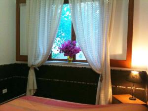 a bedroom with a window with a vase of purple flowers at Apartment in Villa Sea Horizon Sand Beach in Cefalù