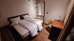 a bedroom with a bed with white sheets and a desk at Cocopark Hotel in Rwinkwavu
