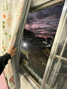 a person is reaching for a window curtain at Santana hospedagem in Cabo Frio