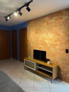un soggiorno con una TV su un muro di mattoni di Apto confortável em condomínio fechado Petrolina a Petrolina