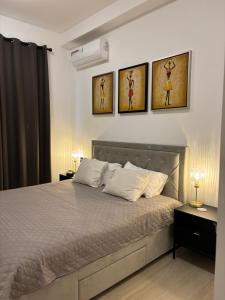 a bedroom with a bed with four paintings on the wall at Stunning Oceanview 2B Waterfront Apartement in Bijilo +29 photos