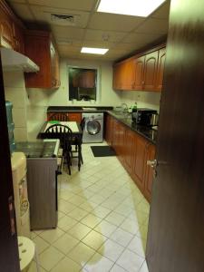 a kitchen with wooden cabinets and a table and a dining room at Ilyas by Smart Home Vacation Homes in Sharjah