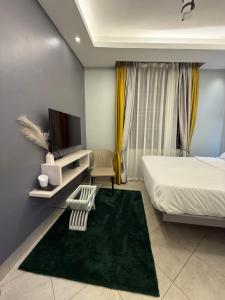 Un dormitorio con una cama y un televisor y una alfombra verde. en Klassroom Hostelry, en Kampala