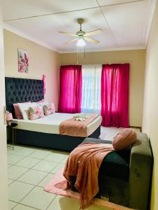 a bedroom with two beds and pink curtains at Rainbow Palace in Bloemfontein