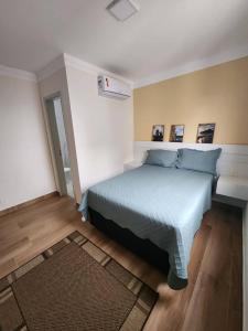 a bedroom with a bed with a blue comforter at Lazer de resort e vista marcante in Guarujá