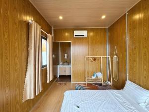 1 dormitorio con paredes revestidas de madera y 1 cama en Cây Trôm Homestay, en Ninh Hải