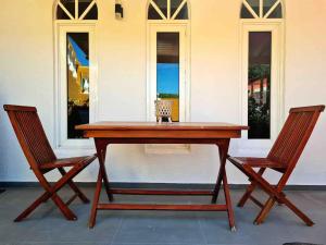 Una mesa de madera con dos sillas al lado de un edificio. en Beautiful Apartment Curacao, en Willemstad