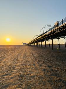 a pier on the beach with the sunset in the background at Lethbridge Villa 49 3-bedroom Apartment with private HOT TUB,Fibre WiFi, free parking, sleeps 6 in Southport