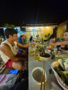Un grupo de personas sentadas en una mesa comiendo comida en Cây Trôm Homestay, en Ninh Hải