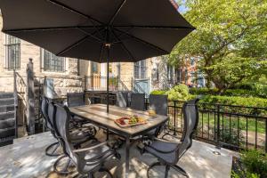 a table with chairs and an umbrella on a balcony at Luxury 2BR & Parking in Heart of DC - Steps to Metro in Washington