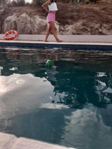 una donna che cammina vicino a una piscina con una palla nell'acqua di Quinta da Peça Douro Wine Region Retreat, Private Pool Villa a Vila Real