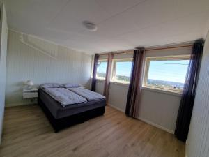 a bedroom with a bed and two windows at Comfortable Apartment Sleeps 3 Near Kristiansand City Center in Kristiansand