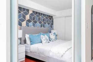 a bedroom with a white bed with blue pillows at Charming Condo w Private Patio in Quiet Capreol in Toronto +17 photos