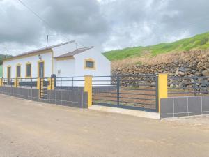 a white building with a fence next to a road at Chalé da Ribeira in Praia da Vitória