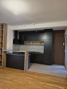 a kitchen with black cabinets and a wooden table at Family Apartment Durmitor in Žabljak +1 photo