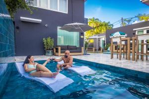 ein Mann und eine Frau sitzen auf Polstern in einem Schwimmbecken in der Unterkunft El Carlton - KingRoom Pool - Resort Vibe Near Beach in San Juan + 13 Fotos