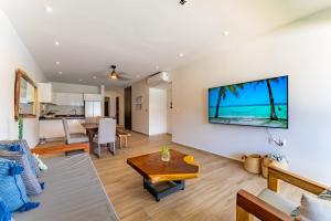 a living room with a table and a tv on a wall at Lagoonfront Apartment with Pool and Beach Access in Puerto Aventuras